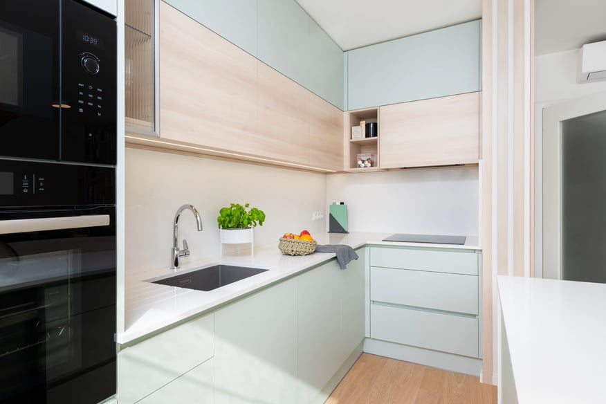 Světlá kuchyně s dřevěnými a zelenými skříňkami, moderní design.